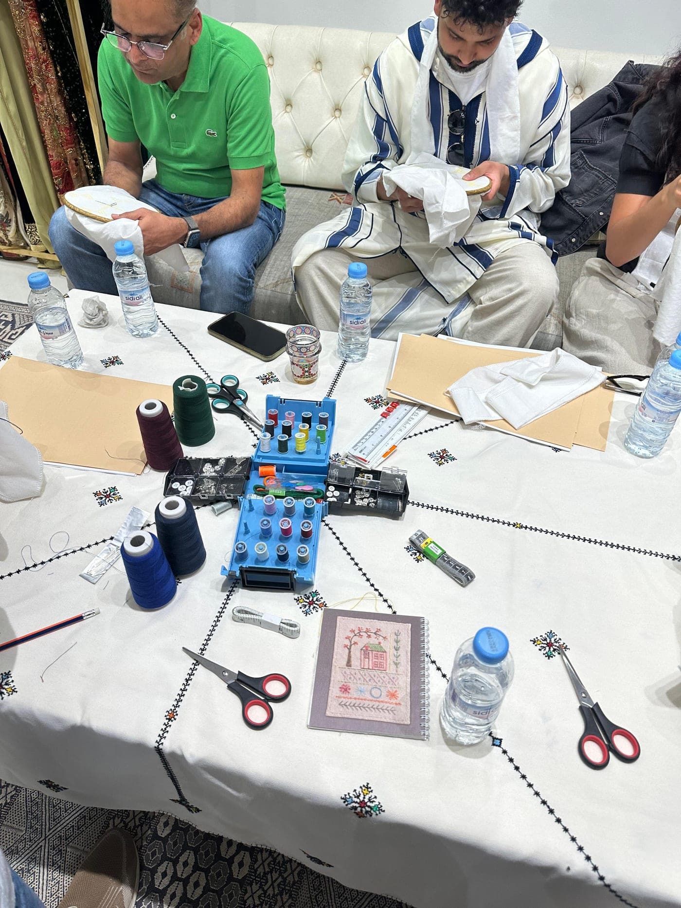 Workshop guests practicing embroidery with a Maalma artisan